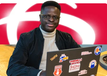 Jovem participante do Programa de Estágio Bradesco em frente ao computador, com logo do Bradesco ao fundo.