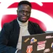 Jovem participante do Programa de Estágio Bradesco em frente ao computador, com logo do Bradesco ao fundo.