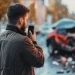 Homem usando celular próximo a local de acidente de trânsito, representando a proibição de divulgar imagens não autorizadas de vítimas.