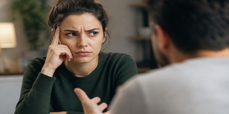 Mulher escuta com expressão contrariada durante uma discussão, situação em que a frase "você me fez sentir" costuma aparecer e transferir ao outro a responsabilidade pelas emoções