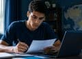 Estudante revisa documentos para a inscrição no Fies 2026 do segundo semestre, com um mapa do Brasil ao fundo representando a distribuição das vagas por estado e região.