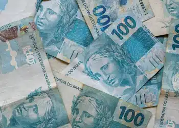 Notas de 100 reais simbolizando pagamentos do INSS em julho de 2026, com destaque para o teto de benefícios de R$ 8.475,55 e consulta via Meu INSS.