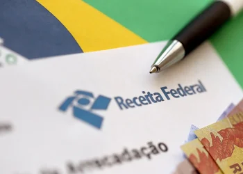 Documento da Receita Federal com caneta e cédulas representa a isenção do Imposto de Renda por doença grave.