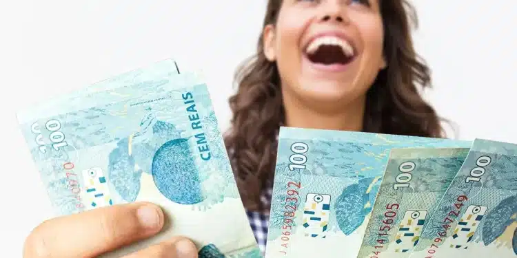 Mulher segurando cédulas de dinheiro representando liberação de pagamento de benefício de R$ 2.621 em julho