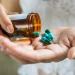 Pessoa segura frasco de medicamento e cápsulas, reforçando a importância da compra em estabelecimentos autorizados.