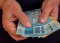 Mãos segurando dinheiro em espécie simbolizando o pagamento de benefícios do INSS de acordo com o calendário