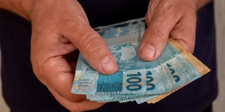 Mãos segurando dinheiro em espécie simbolizando o pagamento de benefícios do INSS de acordo com o calendário