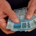 Mãos segurando dinheiro em espécie simbolizando o pagamento de benefícios do INSS de acordo com o calendário