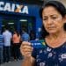 Mulher observa o cartão do INSS com expressão preocupada em frente a uma agência da Caixa, situação de quem teve o benefício não depositado.