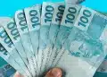 Notas de R$ 100 representando o pagamento, com valor de R$ 1.216 liberado em julho.
