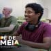 Estudante sorri em sala de aula com colegas ao fundo, ilustrando os alunos da EJA atendidos pelo Pé-de-Meia