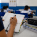 Professora fazendo anotações em agenda durante aula em sala de ensino fundamental, ilustrando investimentos do Fundeb na educação.