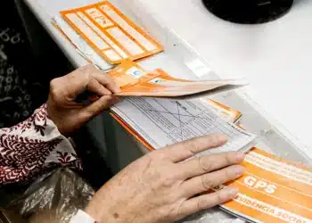 Pessoa segurando carnê GPS e dinheiro para manter a qualidade de segurado do INSS em dia