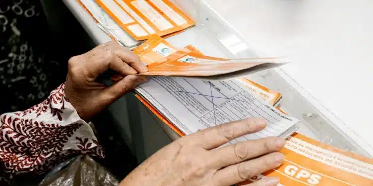 Pessoa segurando carnê GPS e dinheiro para manter a qualidade de segurado do INSS em dia