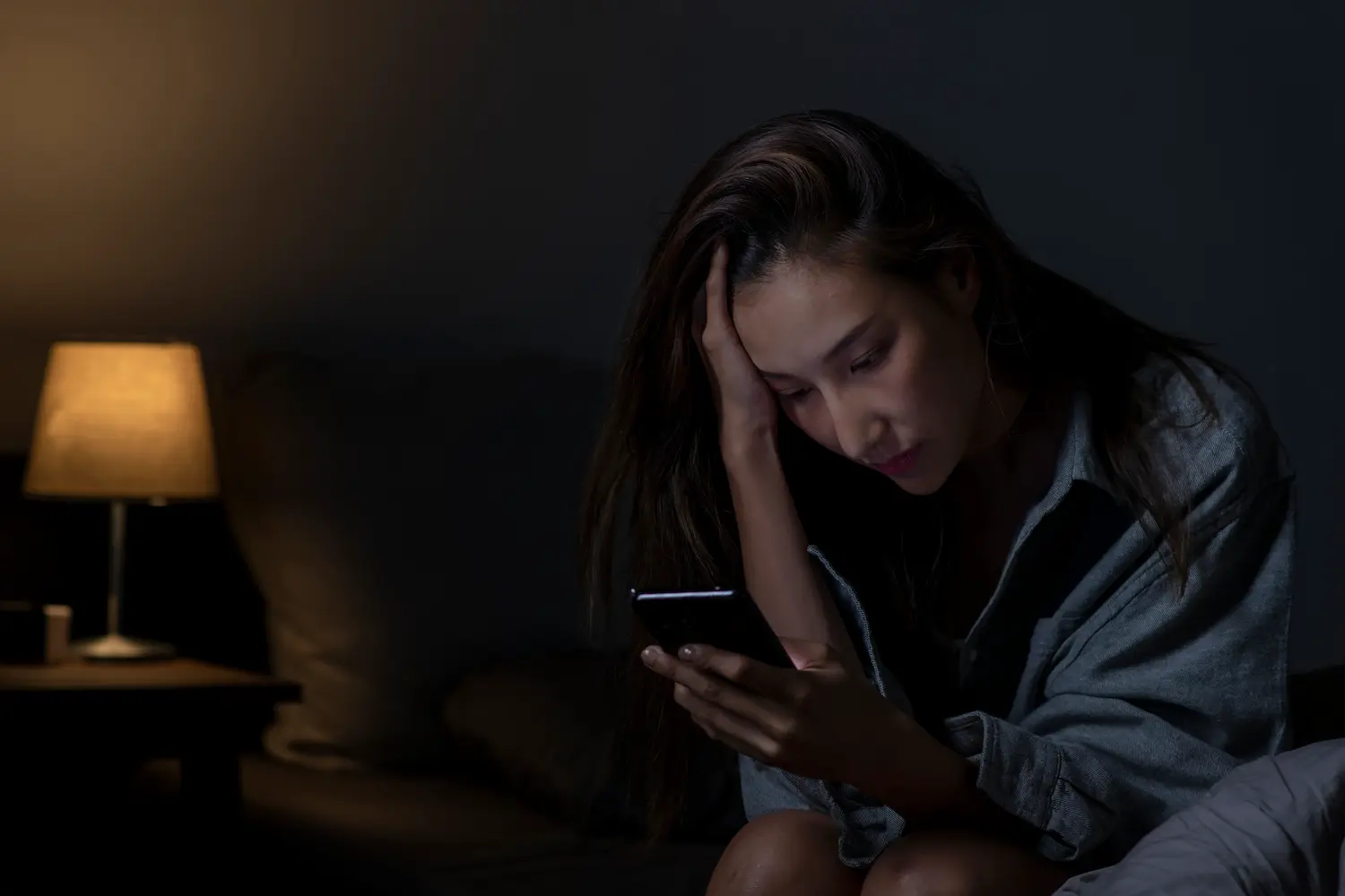 Jovem busca apoio emocional online pelo celular em ambiente residencial.