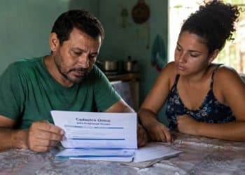 Imagem ilustrativa de um casal analisando um formulário do Cadastro Único em casa, tema da atualização cadastral do BPC.