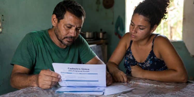 Imagem ilustrativa de um casal analisando um formulário do Cadastro Único em casa, tema da atualização cadastral do BPC.
