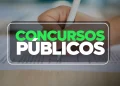 Mão segurando caneta preenche prova objetiva com destaque para texto "Concursos Públicos", simbolizando a preparação para concursos públicos.