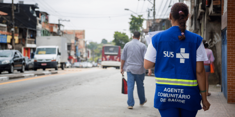 Agente Comunitário de Saúde do SUS realizando atendimento em área urbana durante processo seletivo em Minas Gerais.