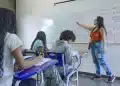 Professora em sala de aula com alunos representando o direito à licença remunerada para qualificação de docentes da rede pública.