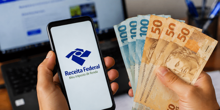 Celular com acesso à Receita Federal ao lado de notas de dinheiro representando dados de renda média dos trabalhadores brasileiros.