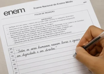 Estudante escrevendo redação do Enem em folha oficial com caneta preta, destacando o uso de citações coringa na prova.