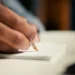 Estudante escreve redação do Enem em folha de papel durante preparação para alcançar nota 1000 na prova.