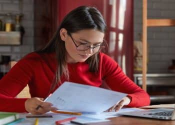 Estudante revisa anotações de gramática ao conferir o plural de palavra-chave e de outros substantivos compostos