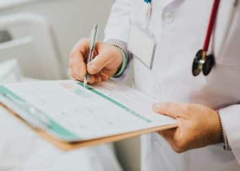 Médico anotando em prancheta, representando o calendário e as etapas do Revalida 2026/2