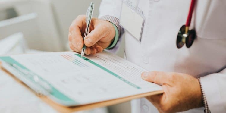 Médico anotando em prancheta, representando o calendário e as etapas do Revalida 2026/2
