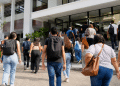 Grupo de jovens e adultos caminhando com mochilas em direção a uma faculdade, representando estudantes interessados no Prouni.