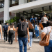 Grupo de jovens e adultos caminhando com mochilas em direção a uma faculdade, representando estudantes interessados no Prouni.
