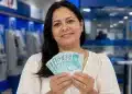 Mulher segura notas de R$ 100 em uma agência bancária, representando o saque de R$ 6.220 do FGTS.