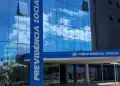Fachada do edifício da Previdência Social (INSS) com reflexo do céu em vidro espelhado, simbolizando melhora no atendimento.