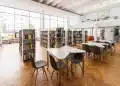 Biblioteca universitária com mesas de estudo e estantes de livros representando as diferenças entre faculdade e universidade.