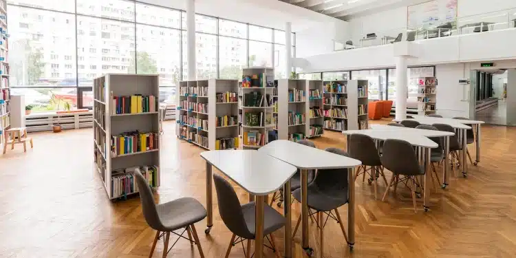 Biblioteca universitária com mesas de estudo e estantes de livros representando as diferenças entre faculdade e universidade.